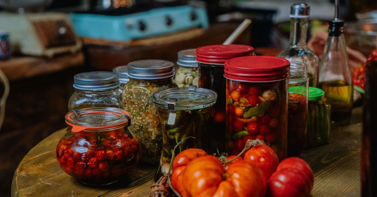 Glass jars with tomatoes and herbs on a wooden table