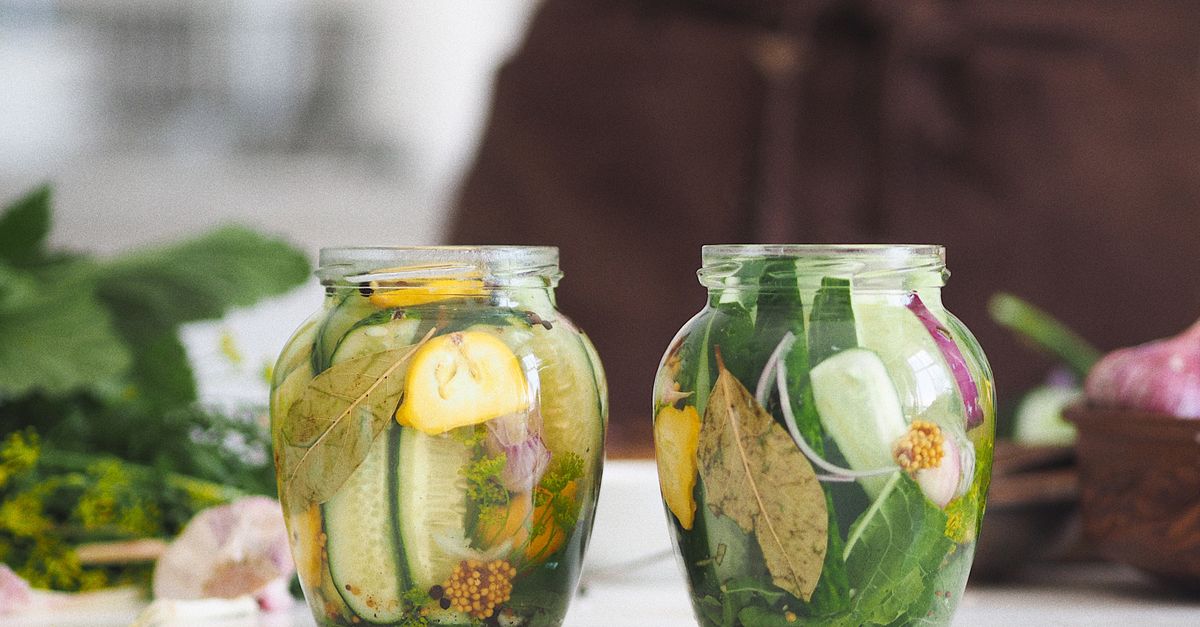 Glass jars with tomatoes and herbs on a wooden table