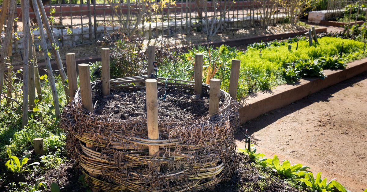 Pila de compost con restos vegetales y hojas secas en un patio